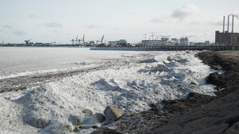 Frozen sea on coast city in cold, sunny winter day.