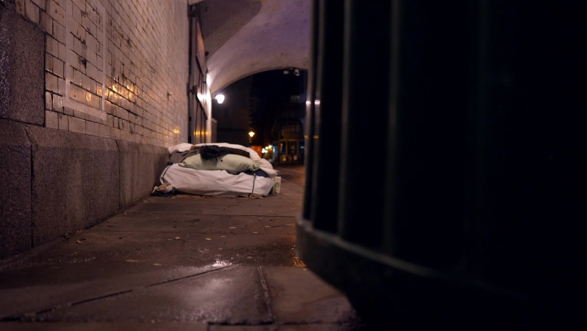 Homeless bed mattress in a tunnel in London at night, on a rainy day, puddles on the ground, poverty problems in cities. Royalty-Free Stock Footage #1068075902