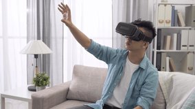 young man playing with VR gadget in living room at home. touching and pointing something in the virtual world.