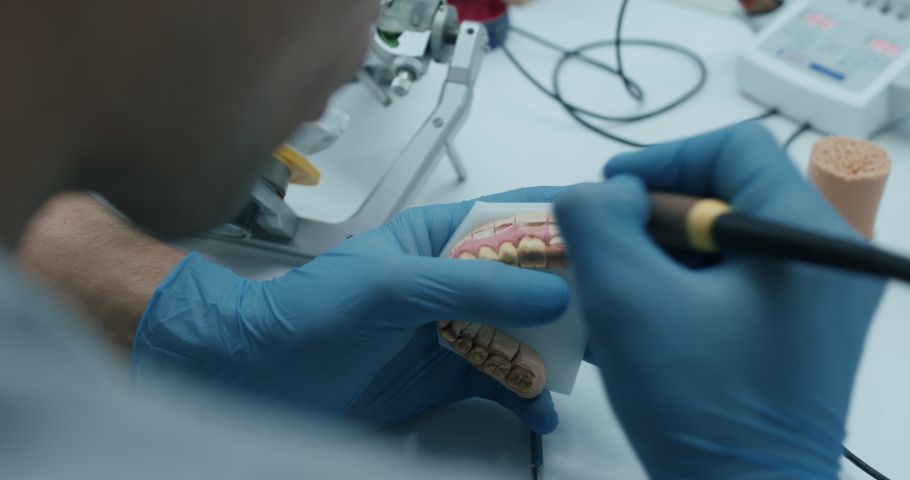 A male technician is holding a lower teeth model, putting it into a articulator yhen testing the dental prothesis working. Royalty-Free Stock Footage #1068094259