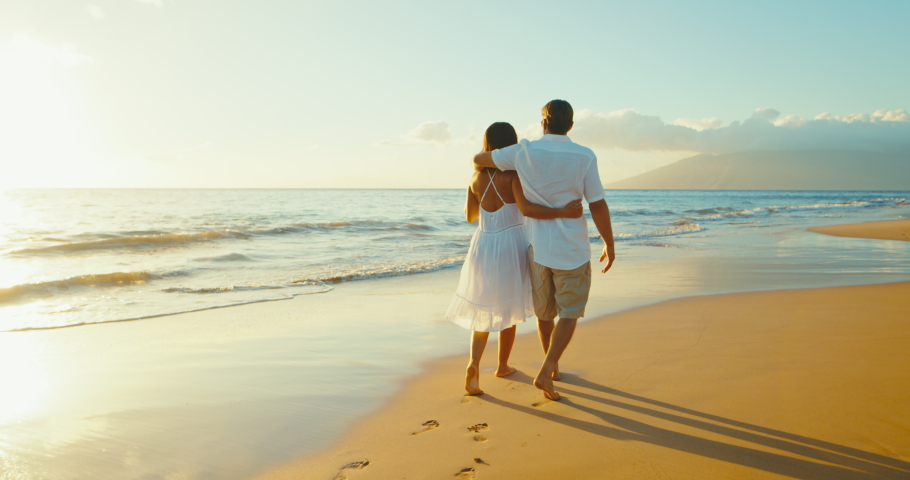 Happy romantic couple enjoying relaxing sunset walk on the beach, travel vacation lifestyle.