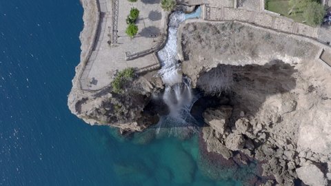 Drone video of a Mediterranean landscape where a river flows through a waterfall into the sea with waves and blue water, a beautiful waterfall on the waterfront in the city. Aerial view Antalya Turkey