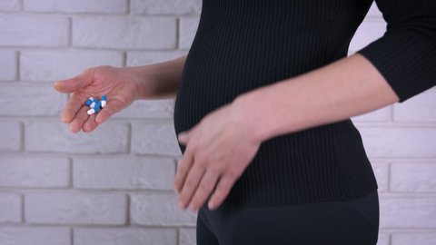 Pregnant woman with pills. A woman think about abortion and suicide and hold pills in her hands.