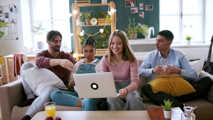 A group of flatmates sitting on sofa and watching movie, house sharing concept.