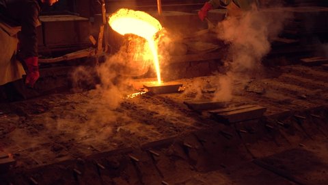 Workers pour hot metal into molds.Industrial worker casting metal at metallurgical factory. Molding molten metal at industrial plant. Manufacturing iron products in heavy industry.Video 4 k.