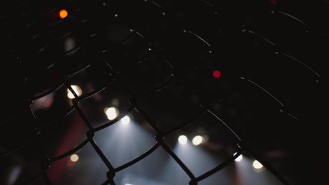 Empty mma cage arena octagon, ring for fights. Light beams flickering, blurred flashing spotlights in background.