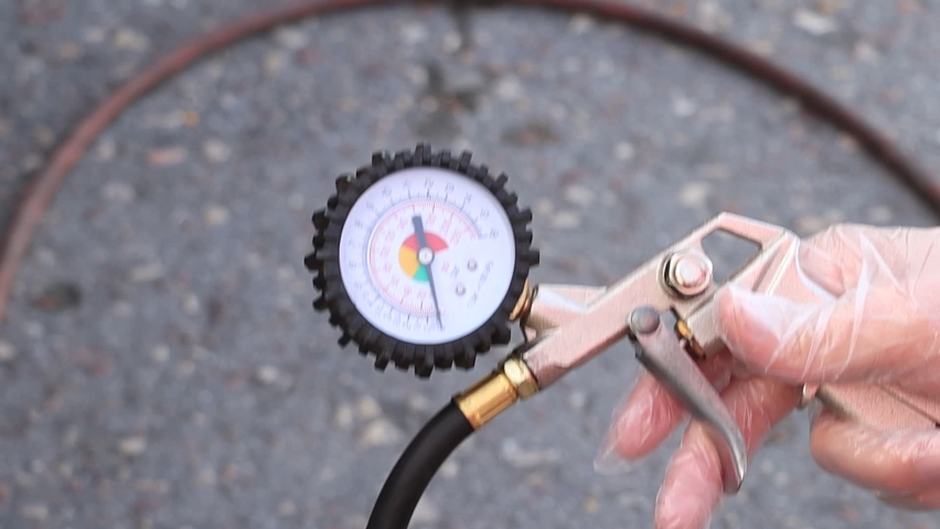 The driver checks the pressure in the wheels of the car.