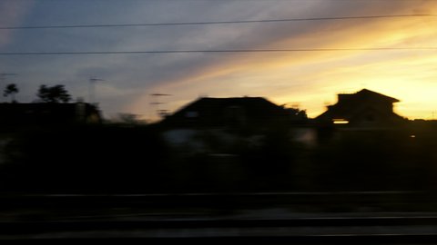 View from the fast train window over the Parisian cityscape with multiple homes and beautiful sunset colored sky