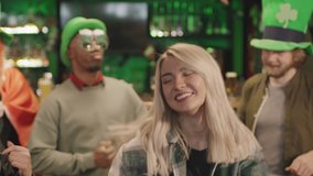 Medium close-up with slowmo of beautiful caucasian woman dancing in front of multi-ethnic friends all celebrating St Patricks Day in local Irish pub - Powered by Shutterstock - Get 15% off with code: PIKWIZARD15