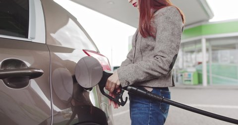 Gas Station Gas Pump Close Up. Pump Nozzles At Gas Station. Young Beautiful Woman Driver Fills The Car With Gasoline. Girl Removes The Gun From The Gas Station And Inserts It Into The Tank Of The Car