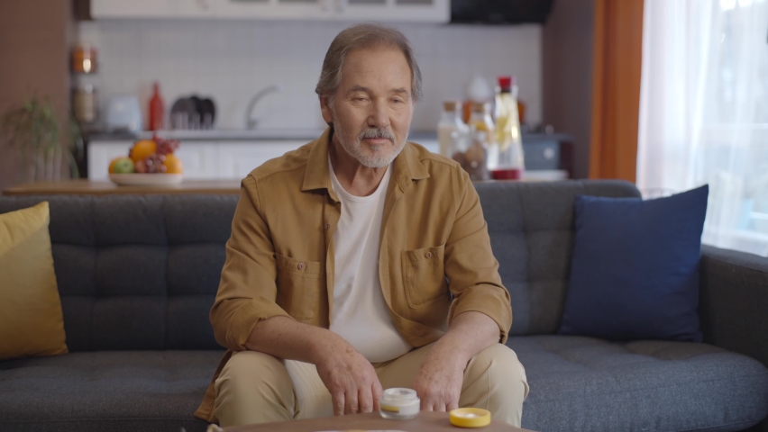 The old man with the beard who put cream on his hands is very happy. Skin cream rub concept.