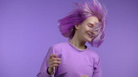 Amazing woman dancing creative hairstyle on violet studio background, Purple hair fluttering from air flow. Hipster girl in positive mood. Slow motion.