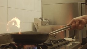 Slow motion of a frying pan in a restaurant kitchen while cooking.HD Super Slow-Mo: Flambeing