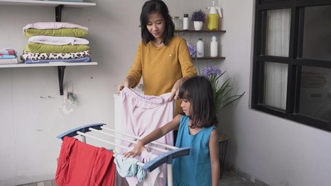 Beautiful young asian woman and child girl little helper are doing laundry at home together