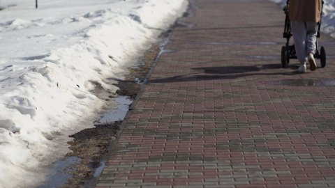 Winter cobblestone sidewalk with snowy sides and people walking calmly outdoor on beautiful sunny warm winter or spring day