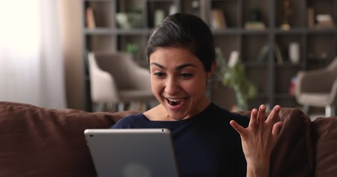 Surprised young happy indian woman looking at computer tablet screen, feeling excited of getting online lottery betting auction win notification, celebrating success at home, good luck concept.