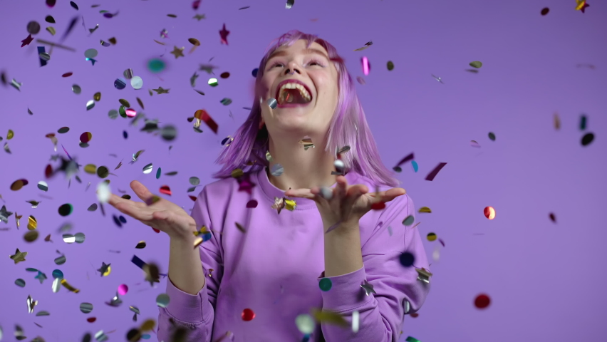 Excited unique woman clapping hands, having fun, screaming WOW, rejoices over confetti rain in studio. Extraordinary girl with violet dyed hairstyle. Concept of celebrating, party, winning | Shutterstock HD Video #1068168452