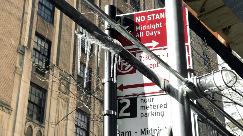 icicles hanging from scaffolding pole and alternate side parking sign in cold winter New York City NYC