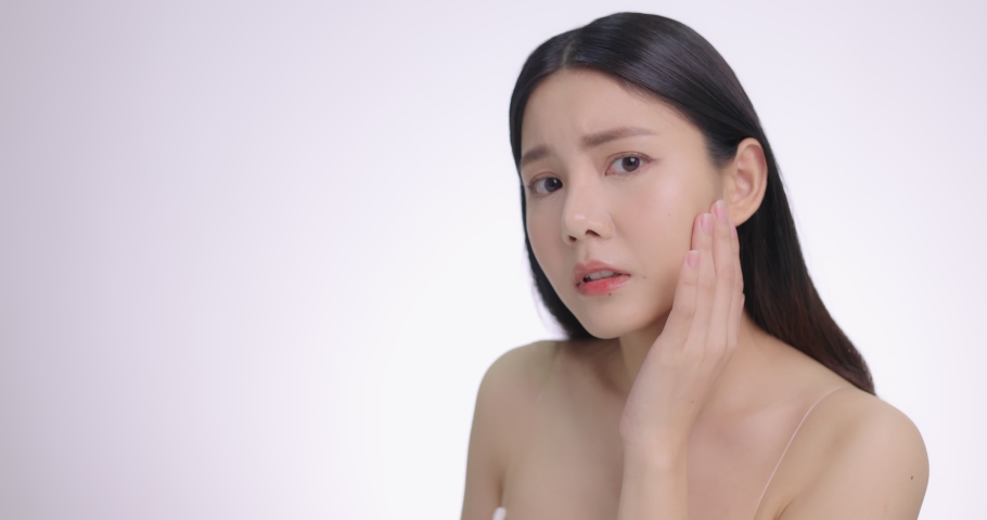 Beautiful Young Asian Woman Touching Her Face Softly. Feeling Worry About Face Skin Care Problem On Cheek. | Shutterstock HD Video #1068170873
