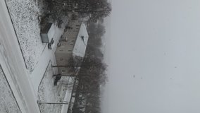 Winter landscape in the town. It's snowing. Snow storm. Car on road. Vertical video.