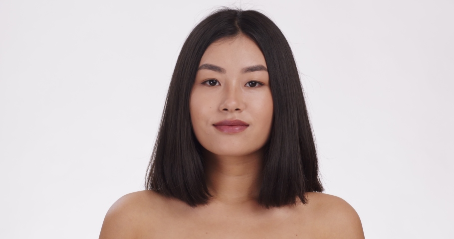 Perfect haircare. Close up portrait of young asian woman playing with her silky hair, white background, slow motion | Shutterstock HD Video #1068185249