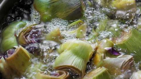 Boiling artichokes in saucepan, closeup at kitchen