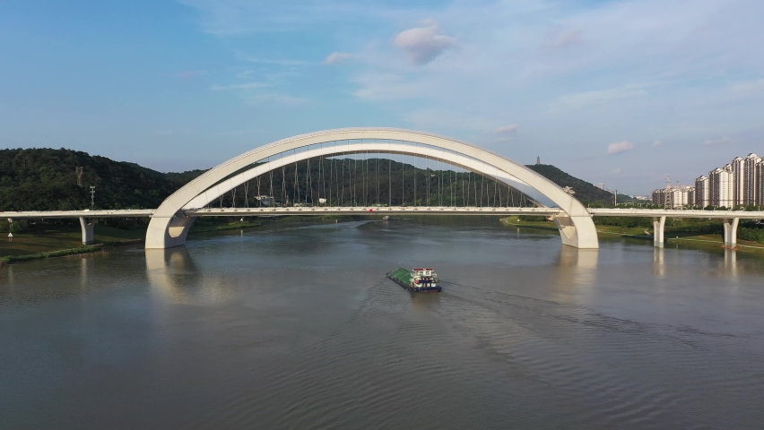 A cargo ship passes a large arched suspension bridge in Nanning, China
