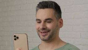 Smiling businessman having video call online at phone camera. Positive professional talking video chat on smartphone at home office. Business man gesturing with hand