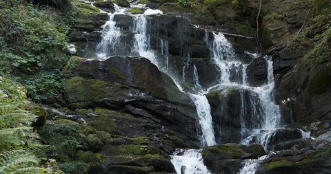 Tilt view of waterfall in the mountains, wild nature of Carpathian Mountains, Ukraine. Cinema 4K 60fps tilt video