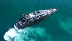 Aerial drone top view video of modern yacht preparing to speed in Mediterranean port with deep blue sea
