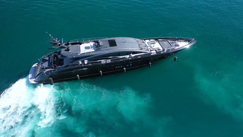 Aerial drone top view video of modern yacht preparing to speed in Mediterranean port with deep blue sea