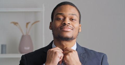 Portrait of afro american confident business man stylish ethnic guy groom preparing for wedding meeting in office wears expensive eligant black suit and blue shirt button up collar looking at camera