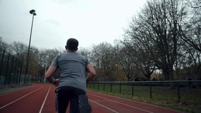Caucasian male athlete running on tracking field checking watch 