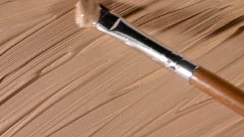 Foundation for face, smear, concealer, cosmetic liquid foundation, make-up smudge or cream beige color smudge, makeup brush. Motion, rotation of the beauty skincare product sample. Macro Shot
