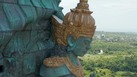 Face of Hindu deity Vishnu in Garuda Wisnu Kencana statue in Bali, Indonesia. Close up aerial view of religious figure on large copper statue rising above the city