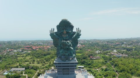 Circling a majestic Garuda Wisnu Kencana statue in Bali, Indonesia. Huge religious monument sculpture of Vishnu riding Garuda rising above the city