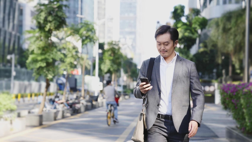 Asian business man walking on street in modern city | Shutterstock HD Video #1068216386