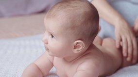 Sweet newborn baby from the back and bottom. Mom takes care of the baby by doing massage. Child development concept. Slow motion 4K video