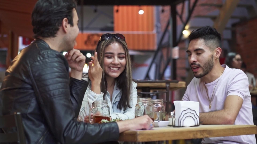 Three people sitting talking while eating tacos | Shutterstock HD Video #1068220970