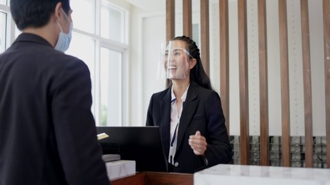 Asian businessman connect with travel Receptionist in airport lounge. Telephone operator to check hotel room Reserve. Mask and face shield to prevent COVID-19 infection. Concept Service business