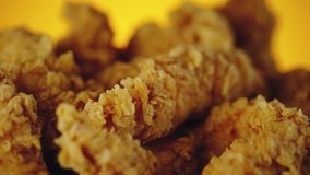 Slow motion video of fried chicken. Close up shot of golden crispy wings, legs and strips