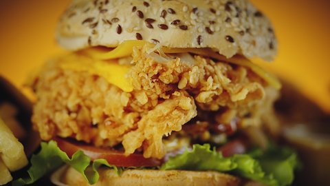 Close up shot with selective focus of crispy chicken burger with cheddar cheese, lettuce, tomato