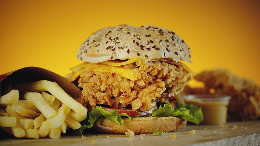 Crispy chicken burger with cheddar cheese, lettuce, tomato, onion. Served with fries and mustard Royalty-Free Stock Footage #1068226955