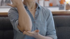 Close-up young woman rubs cream on her elbows. Skincare concept.Slow motion video.
