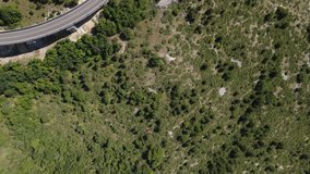 An aerial top view video in high-quality of an empty road located on the top of the hill covered with trees. Shot at midday, on a hot, sunny, summer day in Italian's region Abruzzo.