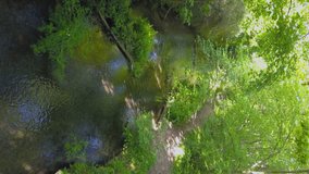 Vertical: mountain biker riding along river trail in summer, aerial view