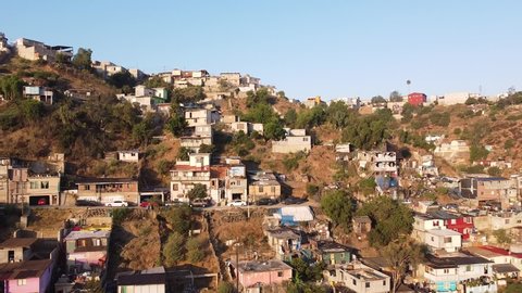Aerial shot pushing in to the slum-filled hills of Tijuana, Mexico, filmed in early-morning light.
