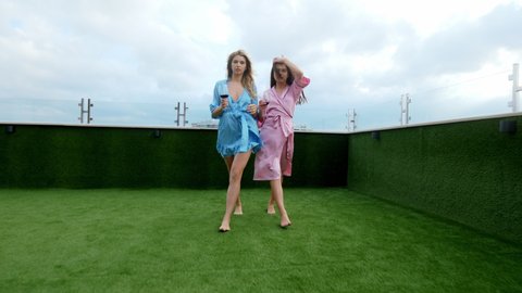 Pretty ladies in romantic pajamas walking in front of the camera on the roof top of loft apartment they are happy and feeling very relaxed in the evening time