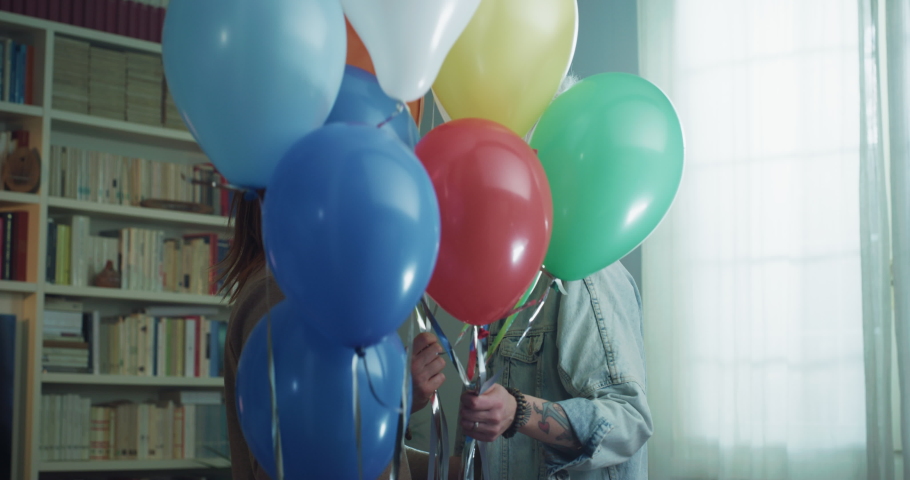 Cinematic shot of carefree happy homosexual female gay and transgender man couple in love enjoying time together is hugging and kissing with floating balloons to celebrate their forever love at home. Royalty-Free Stock Footage #1068238475