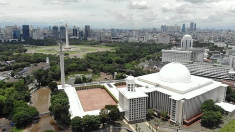 JAKARTA, INDONESIA - FEBRUARY 24, 2021: Cinematic aerial view of iconic Istiqlal Mosque near National Monument of Jakarta or Monas.
